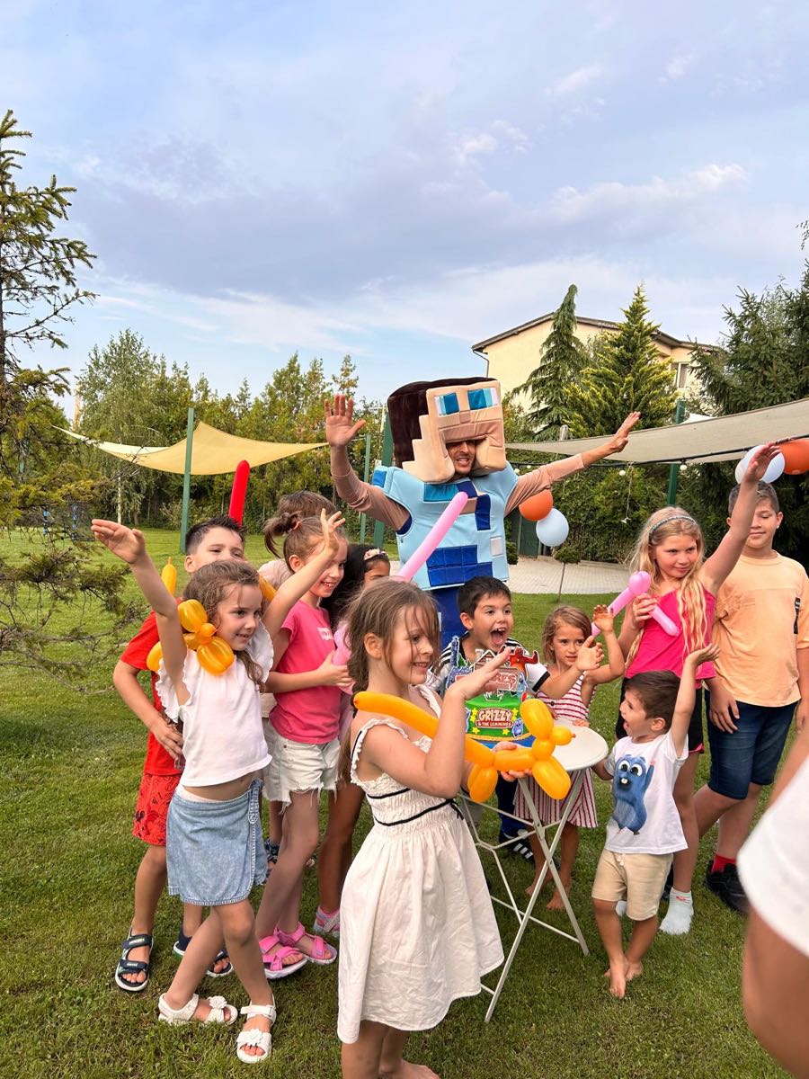 Animator în costum de personaj împreună cu un grup de copii veseli cu baloane modelate, la o petrecere în aer liber
